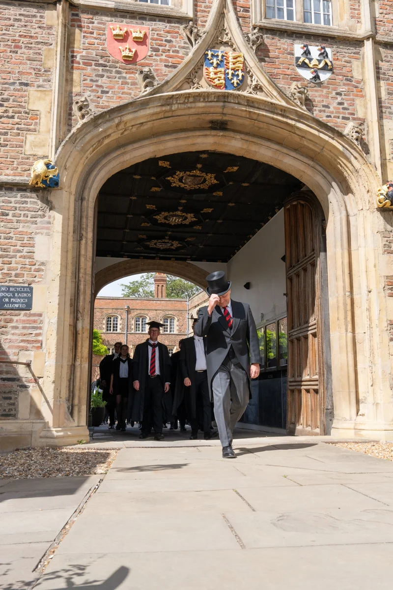 Graduates walking beneath the ornate college gateway