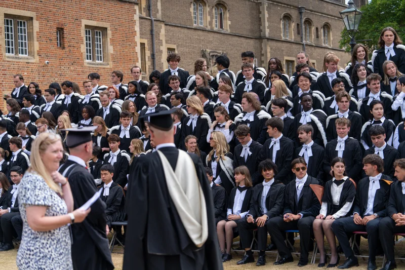 Graduates assembling in rows while a photographer arranges their group photograph