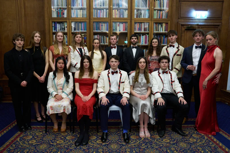 A group in formal evening dress posing in a wood-panelled room