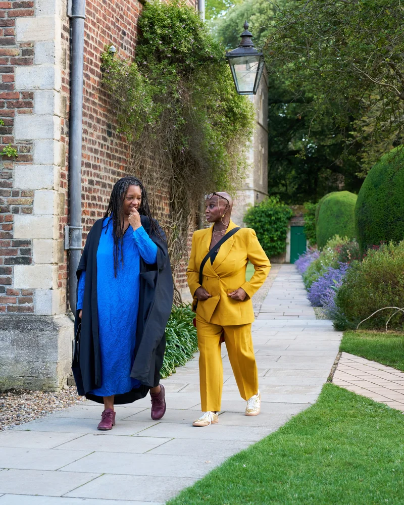 Two people in blue and yellow outfits standing together on a garden path