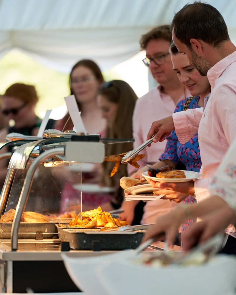 Guests serving food from a buffet at an outdoor reception